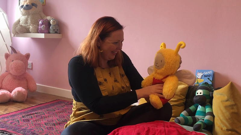 Woman holding Bookbug doll in pink children's bedroom 